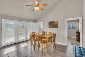 Dining space featuring high vaulted ceiling, ceiling fan, and light tile patterned flooring