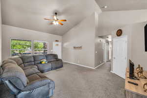 Carpeted living area featuring high vaulted ceiling and a ceiling fan