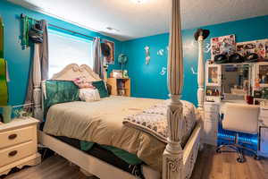 Bedroom featuring wood finished floors, a textured ceiling, and a desk