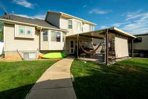 Rear view of house with a yard, a shingled roof, and a patio