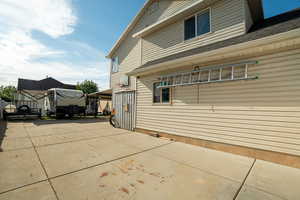 View of home's exterior with concrete driveway, a shingled roof, and a patio