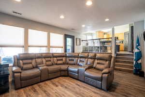 Living area with recessed lighting, dark wood finished floors, stairway, and a textured ceiling