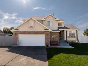 Traditional home with brick siding, concrete driveway, a gate, an attached garage, and stucco siding