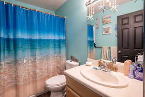 Bathroom featuring vanity, shower / bath combination with curtain, a textured ceiling, and a chandelier