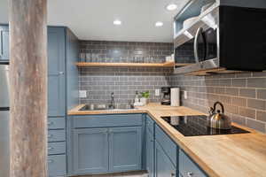 Kitchen with open shelves, appliances with stainless steel finishes, backsplash, blue cabinetry, and recessed lighting