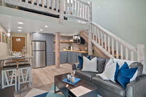 Living area featuring light wood-type flooring, stairway, a towering ceiling, and recessed lighting
