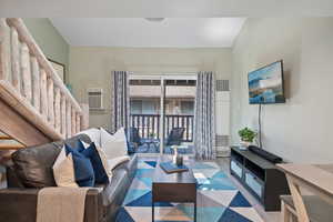 Living area with a heating unit, an AC wall unit, and wood finished floors