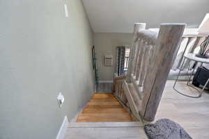 Stairs featuring vaulted ceiling and wood finished floors