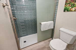 Full bathroom featuring toilet and shower with floor to ceiling tile