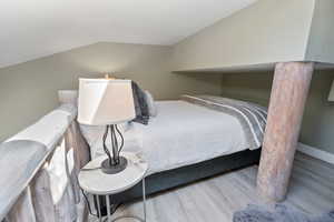 Bedroom featuring light wood-style floors and lofted ceiling