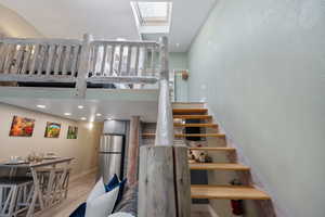 Staircase to lofted bedroom with a skylight, recessed lighting, wood finished floors, and a vaulted ceiling