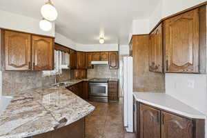 Kitchen with tasteful backsplash, electric range, light countertops, and pendant lighting