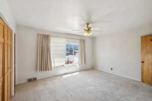 Unfurnished bedroom with a closet, carpet floors, ceiling fan, and wallpapered walls
