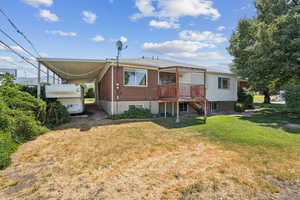 Rear view of house with a carport, a yard, and brick siding