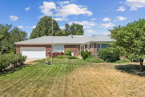 Ranch-style house featuring a garage, a front lawn, brick siding, and concrete driveway