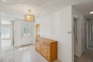 Foyer featuring a textured ceiling, a chandelier, light carpet, and light tile patterned floors