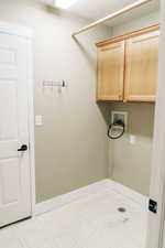 Laundry room with hookup for a washing machine, cabinet space, light flooring, and a textured ceiling