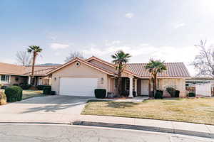 Mediterranean / spanish-style house with an attached garage, driveway, stucco siding, a tile roof, and a front yard