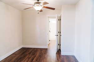 Empty room with dark wood-style floors and a ceiling fan