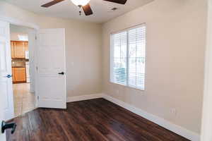 Spare room featuring dark wood-type flooring and ceiling fan