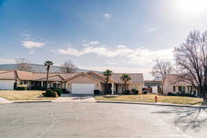 View of front of home with a tile roof, driveway, an attached garage, and a front yard