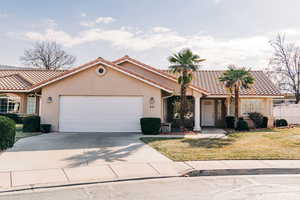Mediterranean / spanish home featuring an attached garage, a tiled roof, and stucco siding