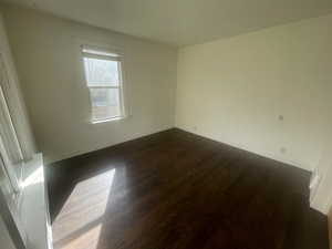 Empty room with dark wood-style flooring and baseboards
