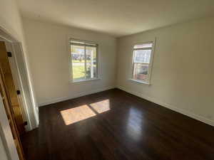 Empty room with dark wood-style flooring and baseboards