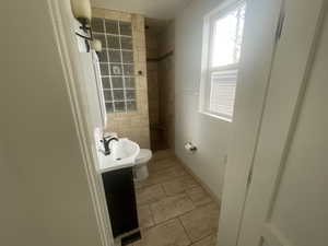 Bathroom with vanity, tiled shower, and light tile patterned floors