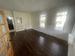Empty room featuring baseboards and dark wood finished floors