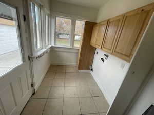 Laundry room with light tile patterned flooring, hookup for a washing machine, cabinet space, and electric dryer hookup