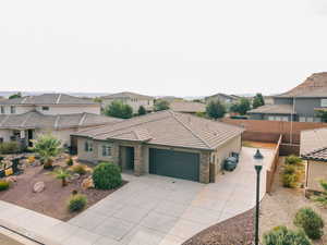View of front of house with a residential view, an attached garage, concrete driveway, stucco siding, and stone siding