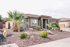 Prairie-style home featuring an attached garage, stone siding, stucco siding, a tiled roof, and driveway
