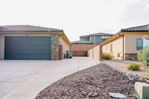 View of home's exterior featuring stone siding, stucco siding, a tile roof, and driveway