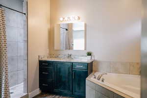 Bathroom with vanity, a garden tub, a shower with curtain, and dark wood-type flooring