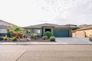 Prairie-style house featuring a garage, driveway, stone siding, and stucco siding