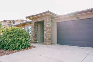 View of front of home with concrete driveway, stucco siding, a garage, and stone siding