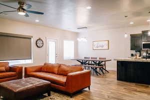 Living room featuring light wood-type flooring, recessed lighting, a textured ceiling, a ceiling fan, and a chandelier