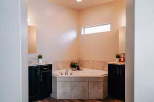 Bathroom featuring vanity, a garden tub, and dark wood-style flooring