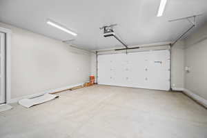 Garage with baseboards and a garage door opener