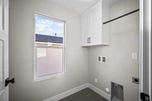 Laundry area with dark tile patterned floors, hookup for a washing machine, cabinet space, and hookup for an electric dryer