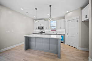 Kitchen featuring white cabinetry, decorative light fixtures, gray cabinetry, recessed lighting, and a center island