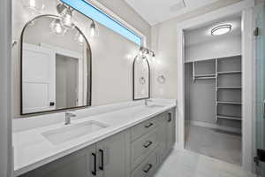 Full bathroom with double vanity, a shower stall, and a walk in closet