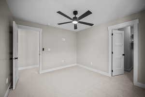 Unfurnished bedroom featuring light carpet and a ceiling fan
