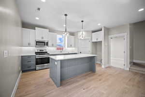 Kitchen featuring gray cabinets, stainless steel appliances, backsplash, white cabinetry, and decorative light fixtures