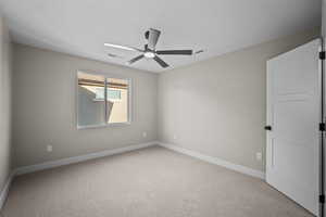Carpeted empty room with baseboards and a ceiling fan