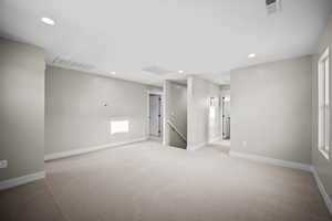 Empty room with light colored carpet and recessed lighting