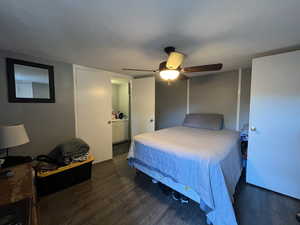 Bedroom with dark wood-type flooring, ceiling fan, and a textured ceiling