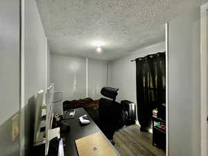 Home office featuring a textured ceiling and dark wood-style floors