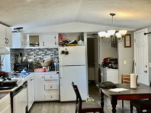 Kitchen with white cabinetry, freestanding refrigerator, a chandelier, light countertops, and a textured ceiling